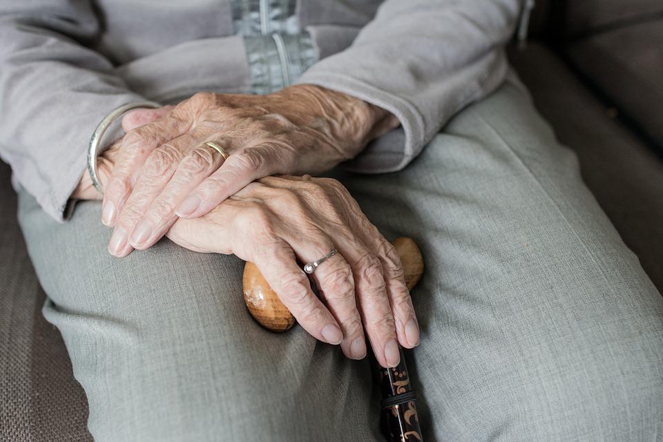 Photo of an old woman’s hand holding a cane