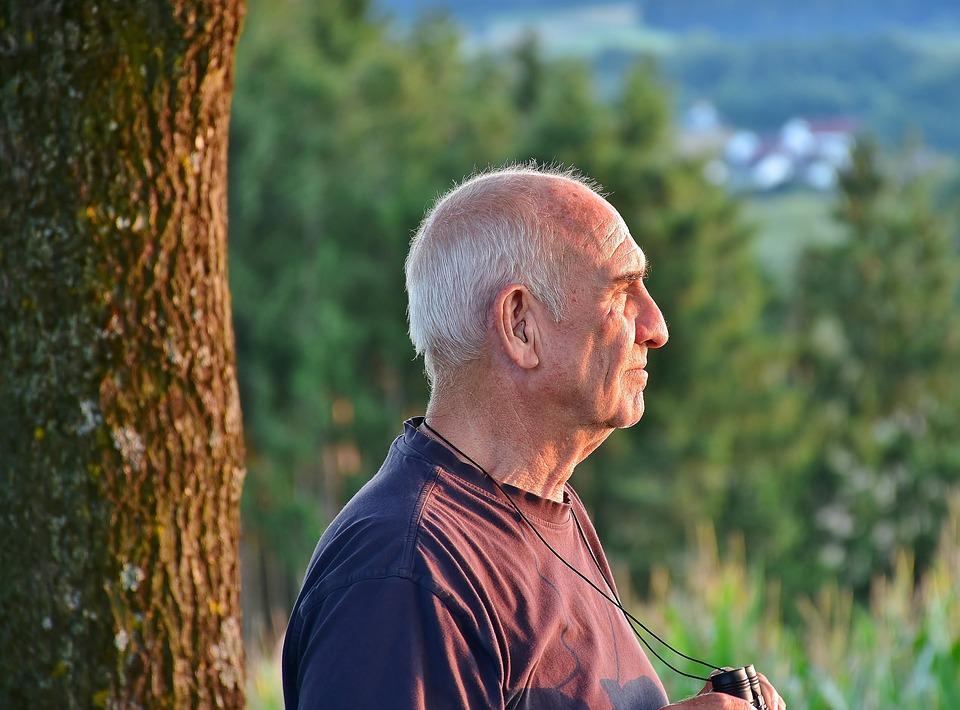 Imageof an old man standing in front of some trees
